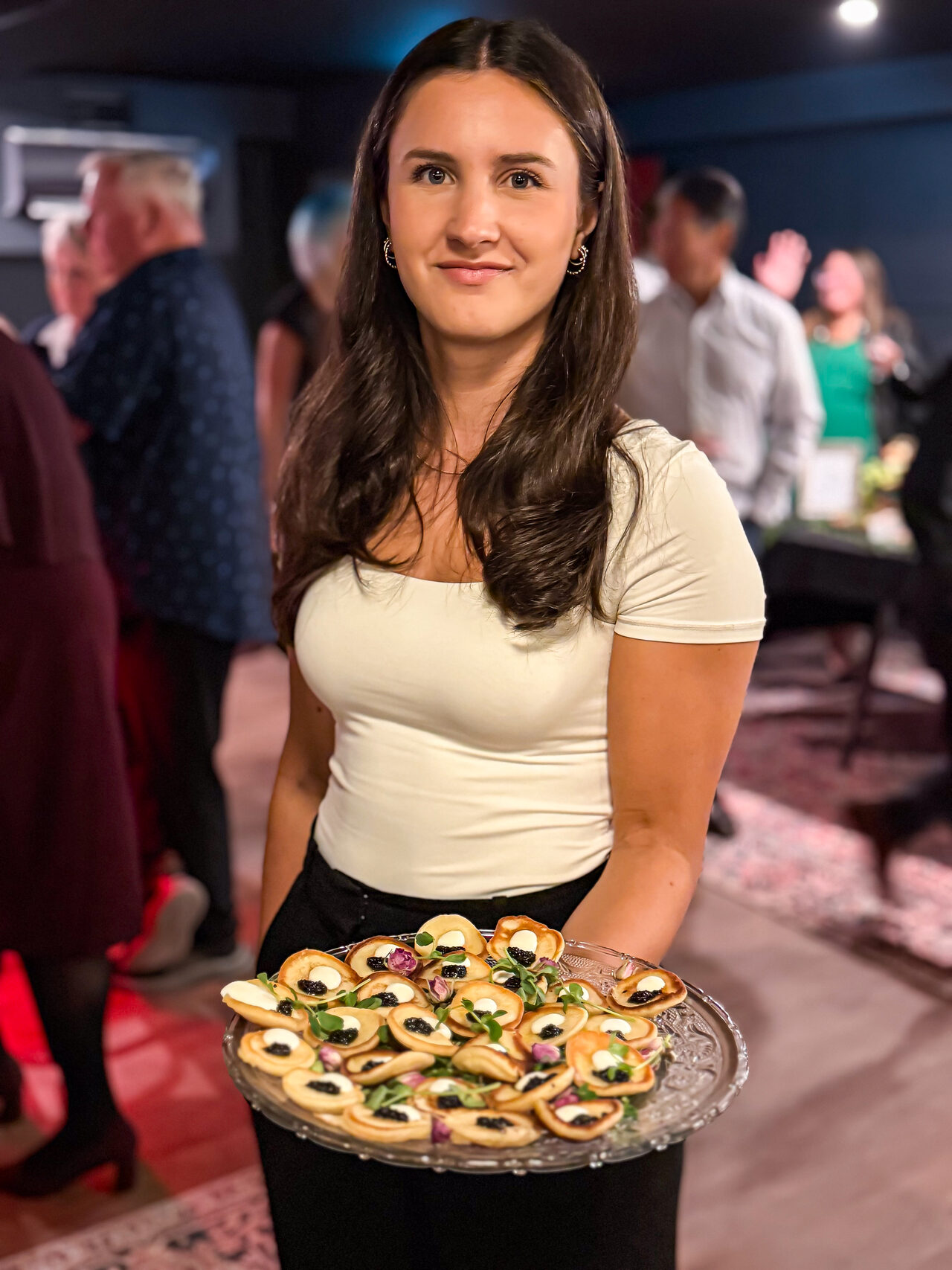 A server carrying plated bites through a First Pour event room